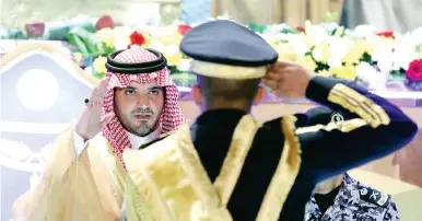  ??  ?? األمير عبدالعزيز بن سعود يبادل أحد الخريجين التحية العسكرية.