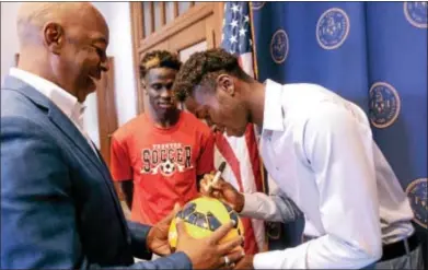  ?? JOHN BERRY — TRENTONIAN PHOTO ?? Matthew Olosunde, right, signs a ball for Trenton Mayor Eric Jackson after a press conference at City Hall Thursday.