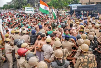  ?? — PTI ?? Police personnel try to stop the farmers protesting over their various demands including the pending promise of 10 per cent developed land ouside Noida Authority on Wednesday.