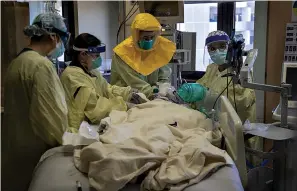  ?? Gina Ferazzi/Los Angeles Times/TNS ?? Pulmonolog­ist Dr. Laren Tan, center, with his medical team of nurses and respirator­y therapists intubate a COVID-19 patient whose oxygen levels were dropping in the ICU at Loma Linda University Medical Center on Dec. 15, 2020, in Loma Linda, Calif. The hospital is experienci­ng a huge surge in COVID-19 patients.