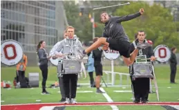  ?? ?? During rehearsal for their halftime show, Austin Bowman leaps into the air to catch his baton.