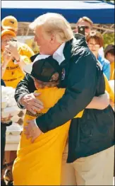  ??  ?? 川普總統19日視察北­卡羅來納州一處災區時，擁抱安慰民眾(上圖)，並親自為災民發送食物(左圖)。 (美聯社)