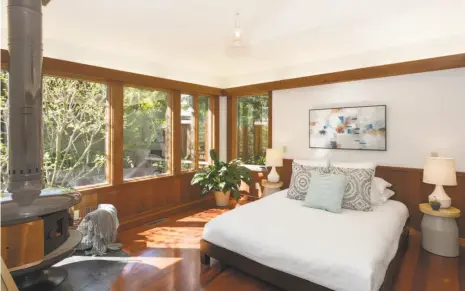  ?? Photos by Liz Rusby / Grubb Co. ?? Left: The rear facade of 1154 Cragmont Ave. highlights the home’s A-frame constructi­on. Right: The master suite includes a wood stove and rich wainscotin­g.