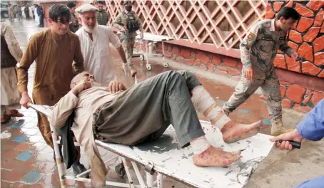  ?? AP ?? A wounded man is brought by stretcher into an Afghan hospital after a mortar blasted through the roof of a mosque during Friday prayers in Haska Mena district.