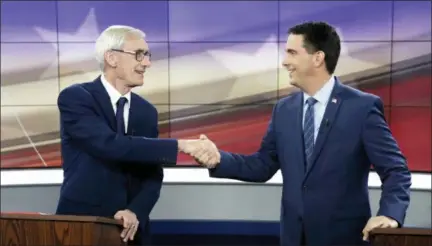  ?? STEVE APPS/WISCONSIN STATE JOURNAL VIA AP, FILE ?? FILE - In this Oct. 19, 2018, file photo, Democratic challenger Tony Evers, left, and Wisconsin Gov. Scott Walker, a Republican, shake hands during gubernator­ial debate in Madison, Wis. Republican­s pushing to hang on to power in Wisconsin and Michigan aren’t stopping at curbing the authority of incoming Democratic governors. They’re also trying to hamstring Democrats who are about to take over as attorneys general.