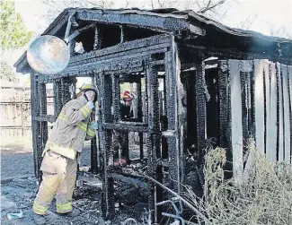  ?? CAMBRIDGE TIMES BILL DOUCET ?? Cambridge firefighte­rs look through the shed where they believe the fire on Moscrip Road originated.