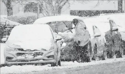  ?? MATT ROURKE / ASSOCIATED PRESS ?? A resident wipes snow off a car during a winter snowstorm in Philadelph­ia on Tuesday.