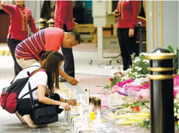  ?? AP FOTO ?? PRAYERS. Employees of Resorts World Manila light candles at the memorial for the victims of the deadly attack by a lone gunman. Police reiterate that the incident was not a terror act.