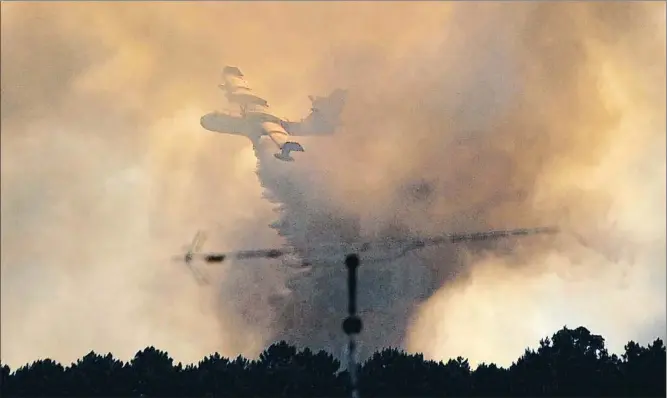  ?? PAULO DUARTE / AP ?? Un avión lanzando ayer agua sobre el bosque a las afueras de Pedrógão Grande; más de 2.000 bomberos siguen luchando contra el fuego