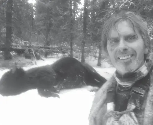  ?? TODD PILGRIM / THE CANADIAN PRESS ?? Natural resource officer Todd Pilgrim with a dead bison on the ground behind him. The Yukon hunter has a harrowing tale of survival after tangling with a bison, the largest land mammal in North America.