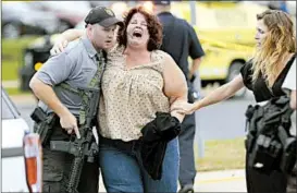  ?? STEVE APPS/AP ?? A woman is escorted away from a software company in Middleton, Wis., on Wednesday after authoritie­s said a gunman fired on his co-workers, seriously wounding three people, and at responding officers before he was fatally shot by police.