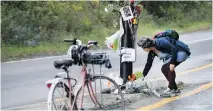  ?? ALLEN MCINNIS ?? A cyclist places flowers Friday at a memorial on Camillien Houde Way for Clement Ouimet who was killed riding his bike this week.