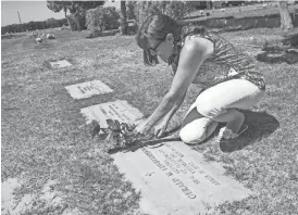 ?? MICHAEL CHOW/THE REPUBLIC ?? Sharon Johnston places flowers at the grave of Spc. 4th Class Gerald Lubbehusen. She is part of a national movement to track down photograph­s of those killed in the Vietnam War.