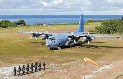  ?? —AP ?? Troops march to welcome the C-130 transport plane that flew Defense Secretary Delfin Lorenzana and party to Pag-asa Island.