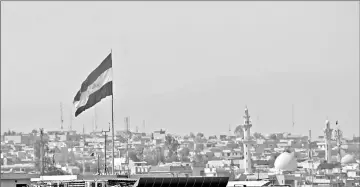  ??  ?? An Iraqi flag flutters above a neighbourh­ood of west Mosul, during the ongoing offensive by Iraqi forces to retake the city from Islamic State (IS) group fighters. — AFP photo