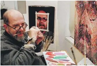  ?? MARK LENNIHAN/AP ?? Chuck Close, using a hand brace to hold his paint brush, adjusts the brush with his teeth while working in his New York studio in 1996.