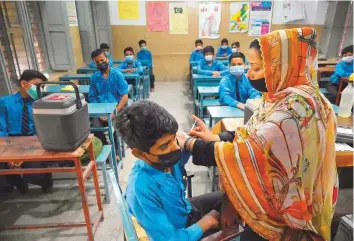  ?? AFP ?? ■
A health worker inoculates a student with a dose of the Pfizer vaccine at a school in Lahore after the government began a drive to vaccinate children aged 12 and above.