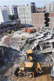  ??  ?? Members of the National Disaster Response Force (NDRF), along with local police, search for victims after an under constructi­on building collapsed in the village of Shah Beri village in Greater Noida.