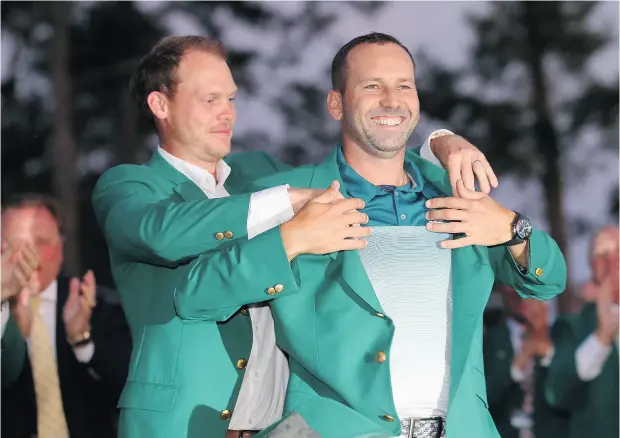  ?? ANDREW REDINGTON / GETTY IMAGES ?? Last year’s Masters champion Danny Willett, left, of England helps Sergio Garcia of Spain with the green jacket after Garcia beat Justin Rose of England in a playoff to win his first major title.