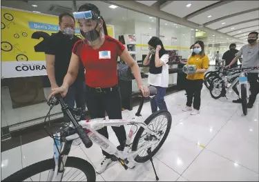  ?? (AP/Aaron Favila) ?? George Canlas (left), founder of the Benjamin Canlas Courage to be Kind Foundation, looks at a recipient pushing a bicycle during a ceremony in the financial district of Manila, Philippine­s.