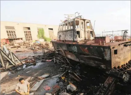  ?? PICTURE: REUTERS ?? A worker walks past a tug damaged by an air strike on the maintenanc­e hub at the Hodeida port, Yemen.