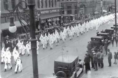  ?? Provided by Denver Public Library ?? Members of the Ku Klux Klan march in a parade on Larimer Street in Denver on May 31, 1926. The city once had a mayor who had joined the Klan and a police chief who was a klansman.