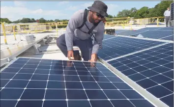  ?? Hearst Connecticu­t Media file photo ?? ENCON employee Andrew Richards installs solar panels on the roof of the Miller Nissan dealership in Fairfield in 2018. The project received financing from Darien-based Greenworks Lending, which has been acquired by financial-services giant TIAA.