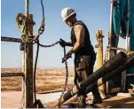  ?? Brittany Sowacke / Bloomberg file ?? A worker prepares to lift drills to the main floor of a drilling rig outside Midland. Oil production costs are low in that area.