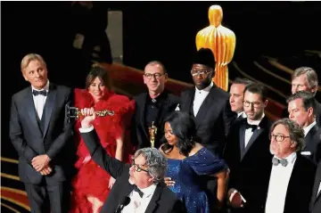  ?? — Reuters ?? Unexpected­win: Farrelly holding up the Oscar as he makes his speech on stage after ‘Green Book’ won the Best Picture award. Looking on are Mortensen (left) and Ali (centre) with other cast members of the film.