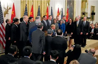  ?? AP ?? President Donald Trump, seated centre, is surrounded by Congressio­nal leaders and Cabinet members as he and Chinese Vice Premier Liu He sign a US-China trade agreement, in the East Room of the White House.