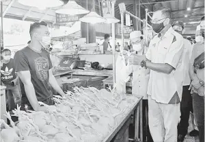  ??  ?? TURUN PADANG: Rosol (kanan) melakukan tinjauan harga ayam yang dilaporkan meningkat sehingga RM10 sekilogram di Pasar Chabang Tiga, dekat Kuala Terengganu semalam.