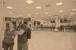  ?? Foto: ap ?? Dos viajeros observan una pizarra informativ­a en medio del caos que se vive en el aeropuerto internacio­nal de Miami por el cierre de salas.