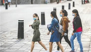  ?? Dav e Sidawa y / Montreal Gazett e ?? Montrealer­s continue to wear masks, including these young women
crossing Notre Dame Street at Place d’armes on Thursday.