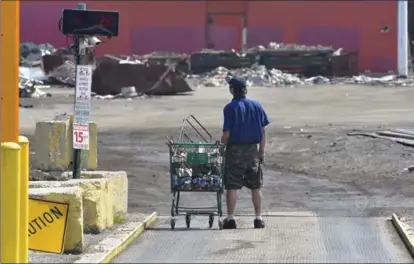  ??  ?? A lone scrapper stands on the weigh scale while heading into Budget Iron and Metals on Sherman Avenue North to drop off his load.