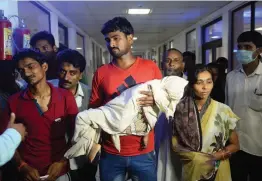  ?? — AFP ?? A man holds the body of a child while walking out of Baba Raghav Das Hospital in Gorakhpur on Sunday.