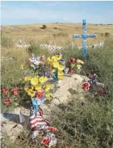  ??  ?? Des tombes ornées d’un cimetière lakota près de l’école. Des vagues de suicides affectent particuliè­rement les jeunes de la communauté.