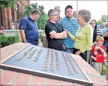  ??  ?? Shelby Barton, front right, comforts Jerry Williams Jr., arms crossed, at the dedication of a memorial for two Dade County, Ga., tornado victims on the anniversar­y of the storms. The memorial is dedicated to Jerry Douglas Williams Sr. and Donald Lee...