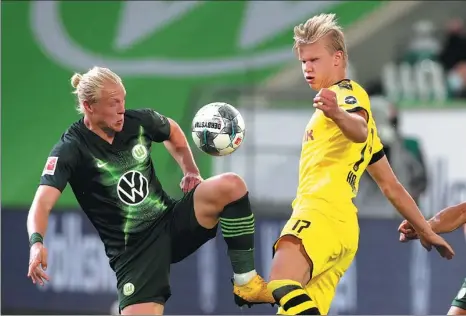  ?? REUTERS ?? Borussia Dortmund’s Erling Haaland (right) battles for possession with Wolfsburg’s Xaver Schlager during Saturday’s match at Wolfsburg. Dortmund won 2-0 to stay perfect two games into the Bundesliga’s restart following its shutdown due to the COVID-19 pandemic.