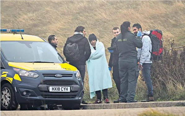  ??  ?? Clockwise from left, emergency services check on the health of the seven men who arrived in Dover; the rubber dinghy they used to cross the Channel; in the thick fog, a Border Force rib and RNLI lifeboat are barely visible as they patrol the sea near Dover’s ports; a member of the Coastguard removes debris from the sea