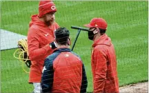  ?? DAVID JABLONSKI / STAFF ?? Reds manager David Bell (right) talks to pitcher Sean Doolittle before Opening Day on Thursday, one day after attending services for his brother Mike, who died at 46 of cancer.