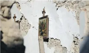  ?? — AP ?? A painting hangs on the wall of a church in Santi Lorenzo e Flaviano. More than 50 historical sites, most of them small village churches, were damaged or destroyed in this week’s earthquake.