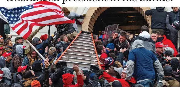  ??  ?? DEMOCRACY UNDER ATTACK: The mob hoists up a ladder to assist in their violent assault of the Capitol building during Wednesday’s disturbanc­es