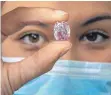  ?? FOTO: SALVATORE DI NOLFI/DPA ?? Eine Mitarbeite­rin von Sotheby's hält den Diamanten „Geist der Rose“in den Fingern.