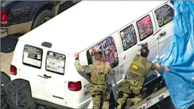  ?? WPLG-TV VIA AP ?? This frame grab from video provided by WPLG-TV shows FBI agents on Friday covering a van that federal agents and police officers have been examining in connection with package bombs that were sent to high-profile critics of President Donald Trump. The van’s tarp fell off as it was being transporte­d from Plantation, Fla.. The van has several stickers on the windows, including American flags, decals with logos and text.