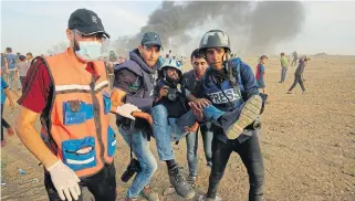  ?? /AFP ?? Line of duty: In this file photo taken on October 5, 2018 Palestinia­n paramedics and journalist­s carry a wounded journalist during clashes with Israeli forces near Gaza City.