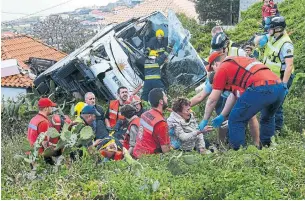  ?? RUI SILVA AFP/GETTY IMAGES ?? Rescue workers help victims of a bus crashed Wednesday on the Portuguese island of Madeira.