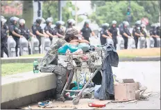  ?? — AFP photo ?? An homeless man sits in front of riot police as members of social organisati­ons gather outside the Ministry of euman Capital to protest against food scarcity at soup kitchens and President gavier Milei’s government’s austerity plan in Buenos Aires.