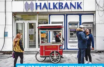  ?? —AFP ?? ISTANBUL: In this file photo, people walk by as a street vendor stands in front of a branch of the Turkish bank Halkbank in Istanbul.