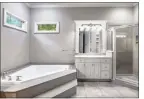  ?? ?? The primary en suite bath offers a luxurious corner spa tub and a step-in glass shower