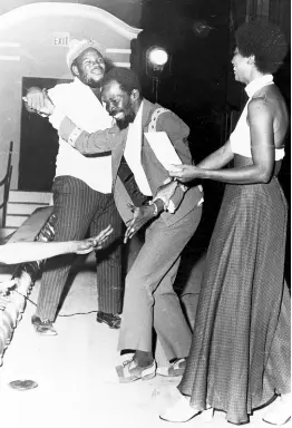  ?? ?? WINNER: Joe Higgs, winner of the Jamaica Tourist Board’s Tourist Song Competitio­n, being congratula­ted by two of his admirers, while Mrs Michael Manley, wife of the prime minister, tries to present him with his prize cheque for $1,000.